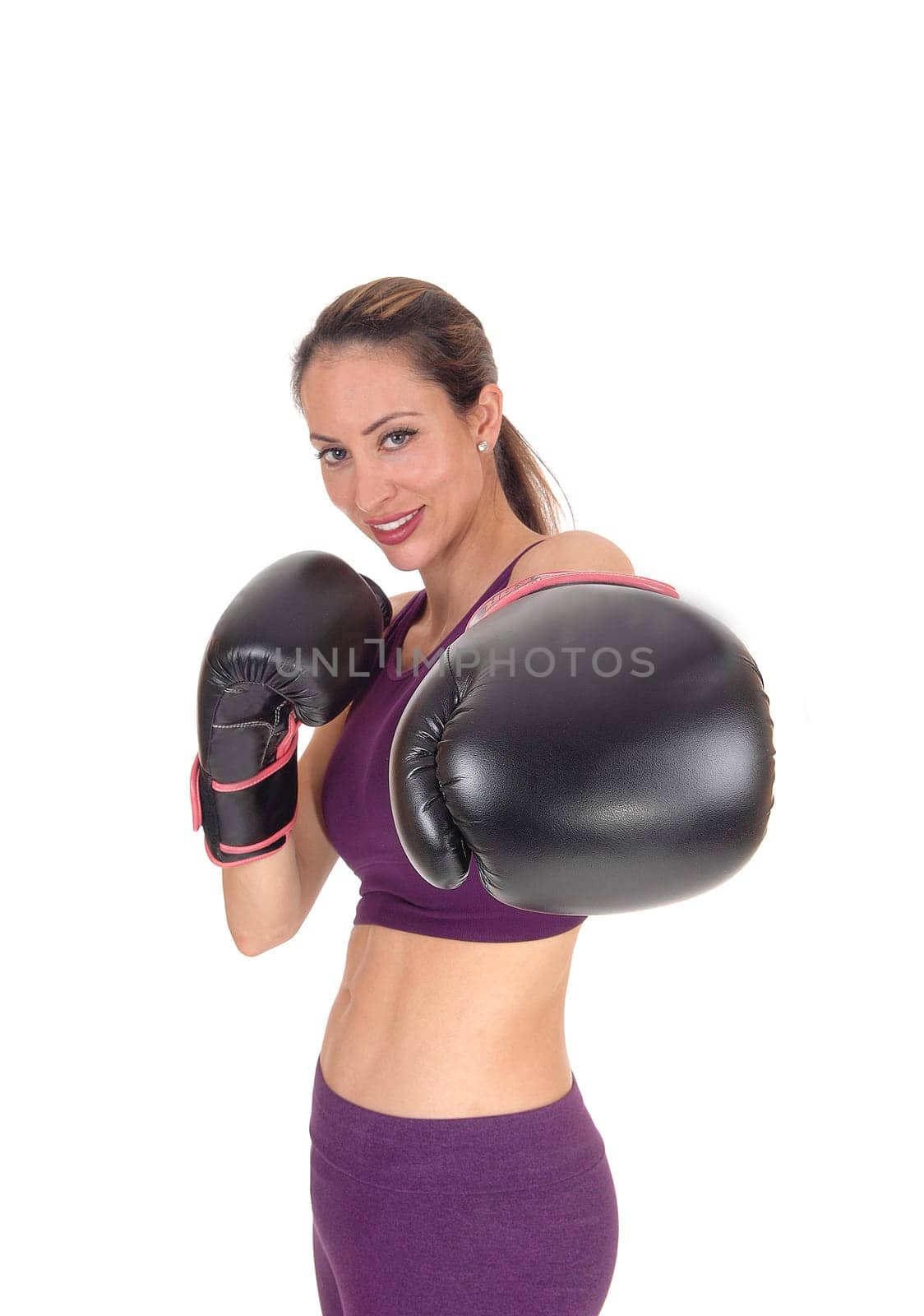 A beautiful woman smiling with her arms up and black boxing cloves.ready to give a punch, isolated for white background.