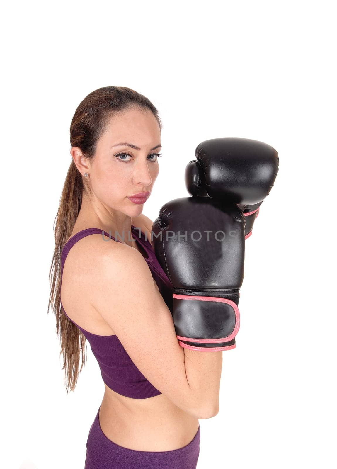 A lovely serious looking woman standing and holding with her black .boxing cloves for a fight, isolated for white background.