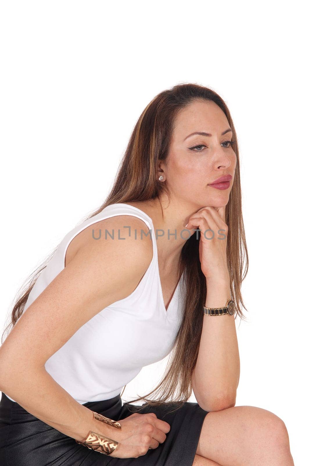 A lovely brunette young woman sitting in a black leather skirt on a.chair with her long brunette hair, isolated for white background.