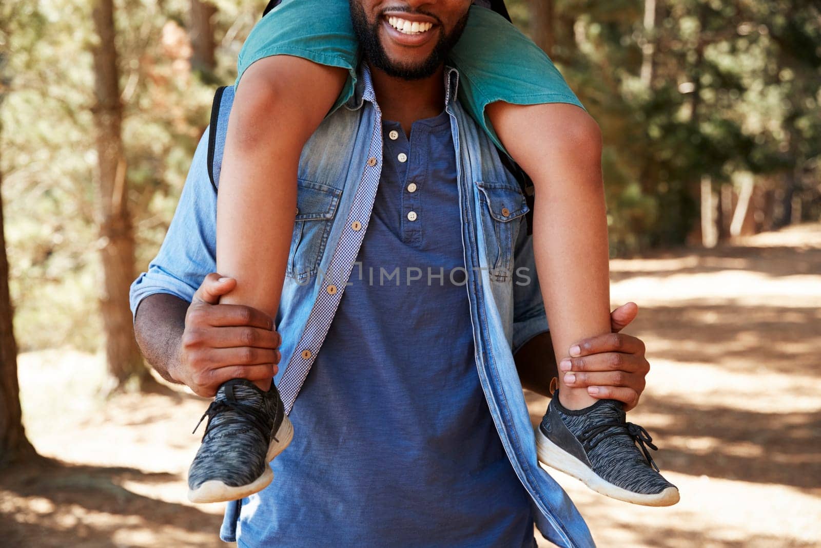 Close Up Of Father Walking In Woods Carrying Son On Shoulders