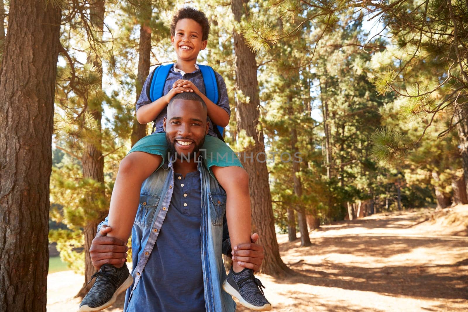 Portrait Of Father Walking In Woods Carrying Son On Shoulders