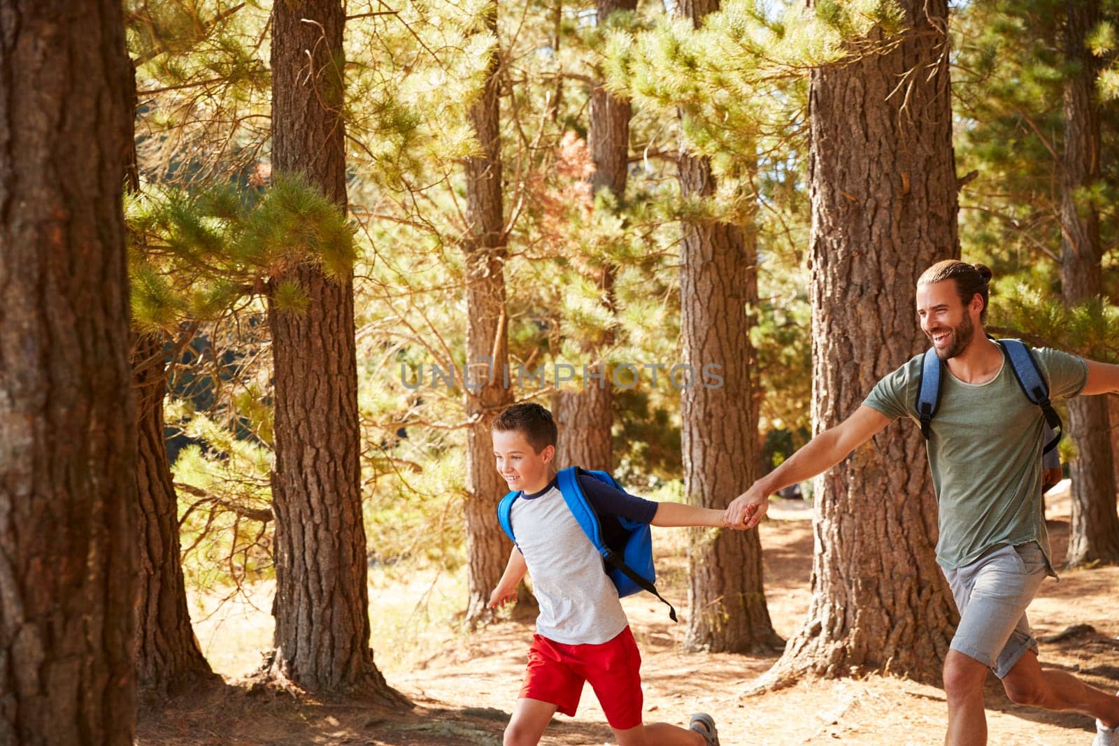 Father And Son On Hiking Adventure Running Through Forest
