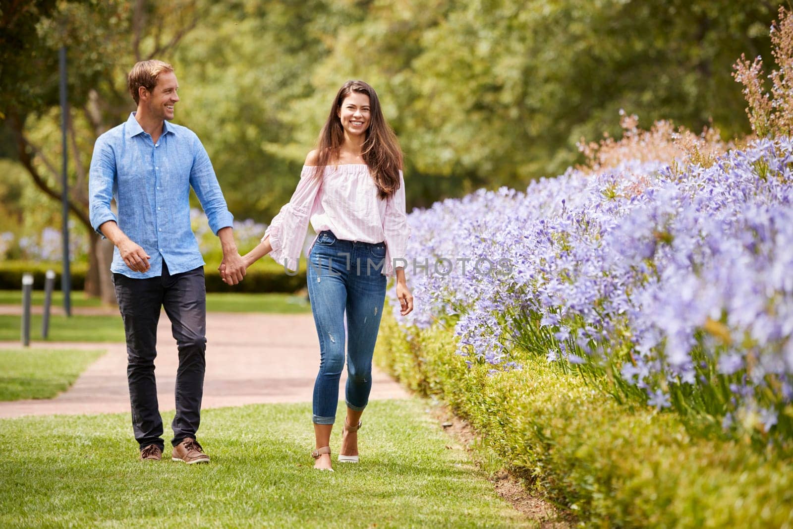 Couple Holding Hands On Romantic Walk In Park Together