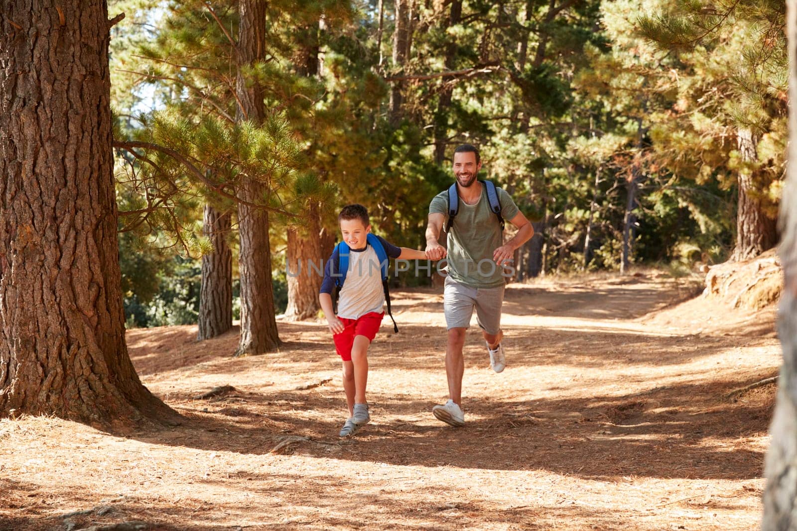 Father And Son On Hiking Adventure Running Through Forest