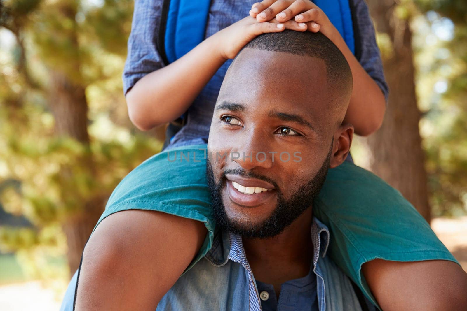 Close Up Of Father Walking In Woods Carrying Son On Shoulders