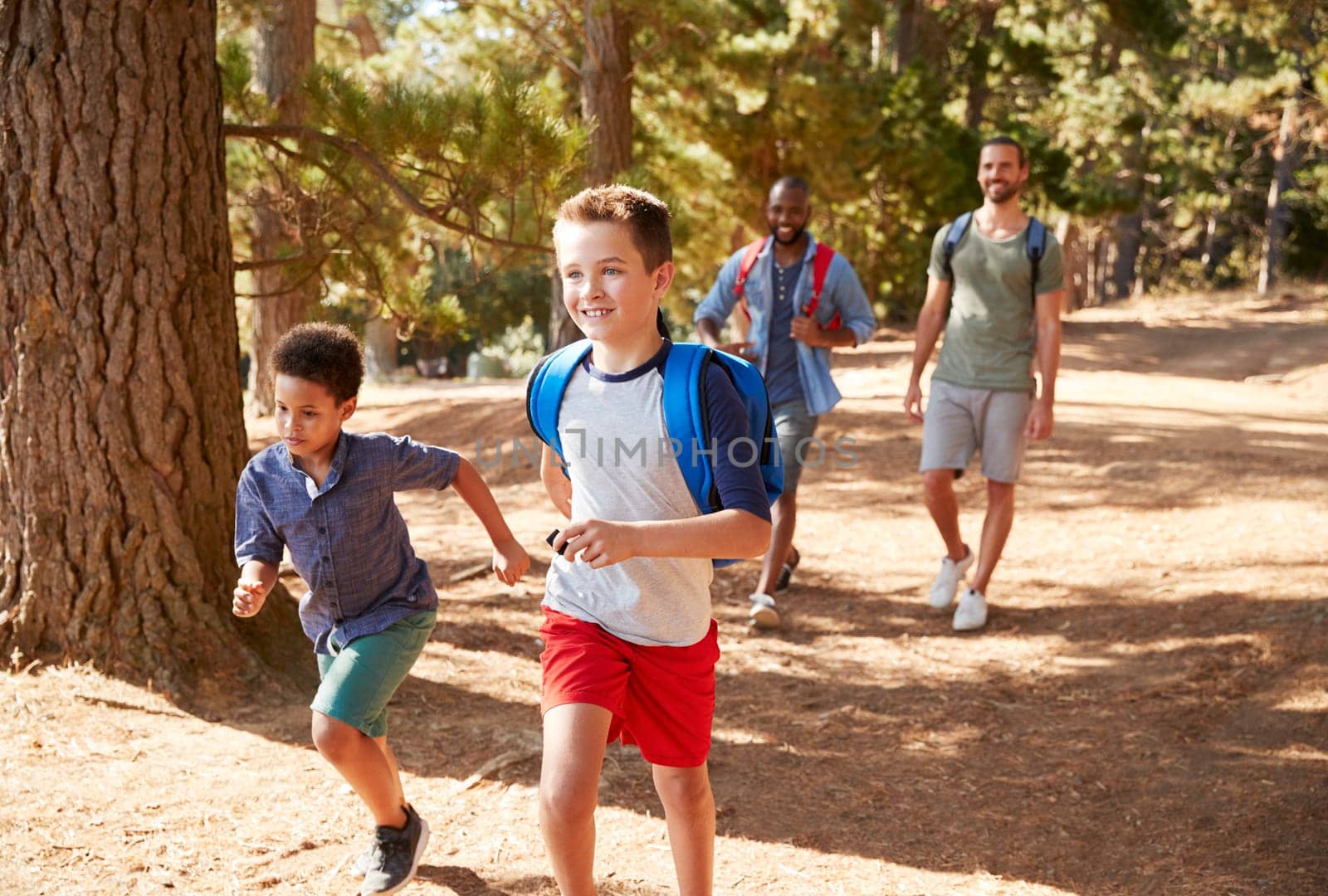 Boys Running Ahead Of Fathers On Hiking Adventure
