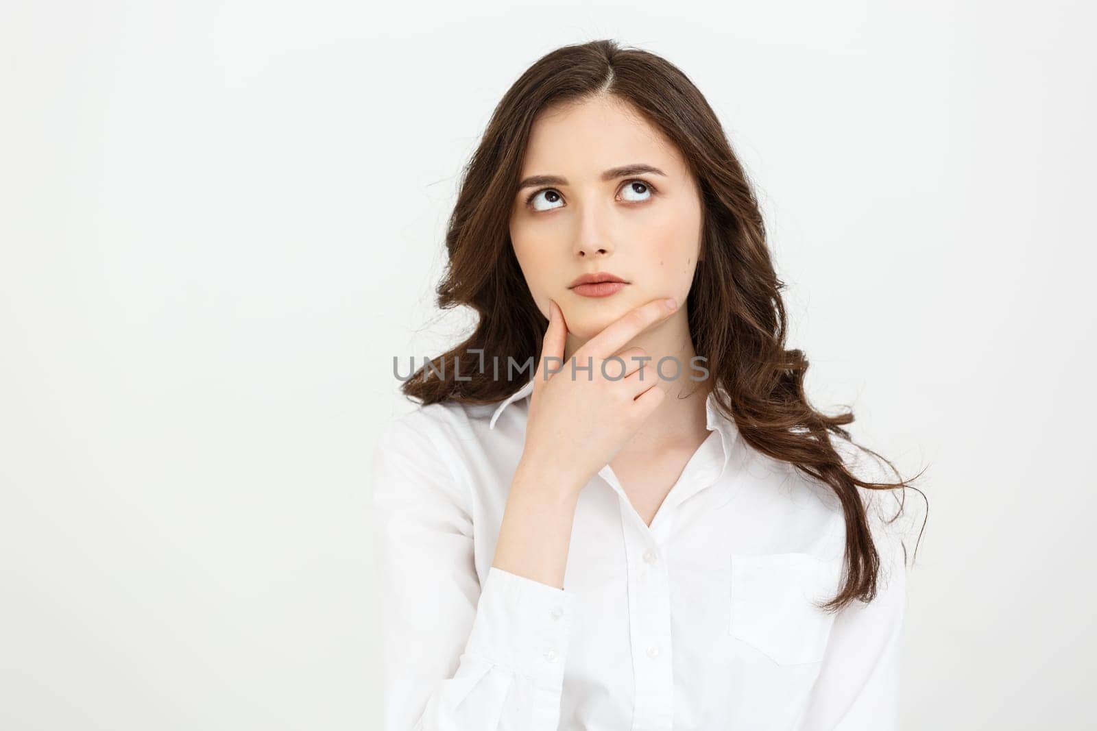 Thinking Caucasian business woman with hand on her chin and looking up on grey backgroud