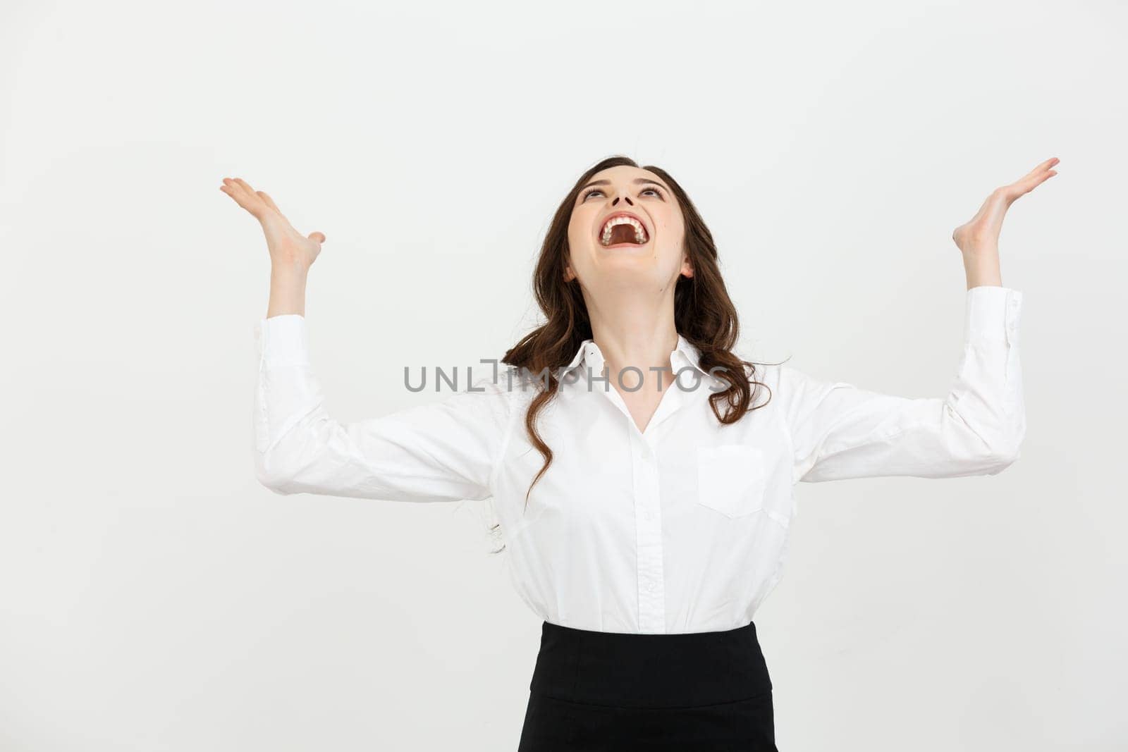 Business Concept: young happy businesswoman with hands in the air is celebrating success on white background.