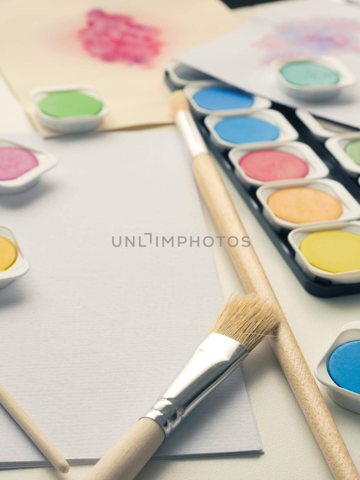 Set of watercolor paint, art brushes and paper on a desk