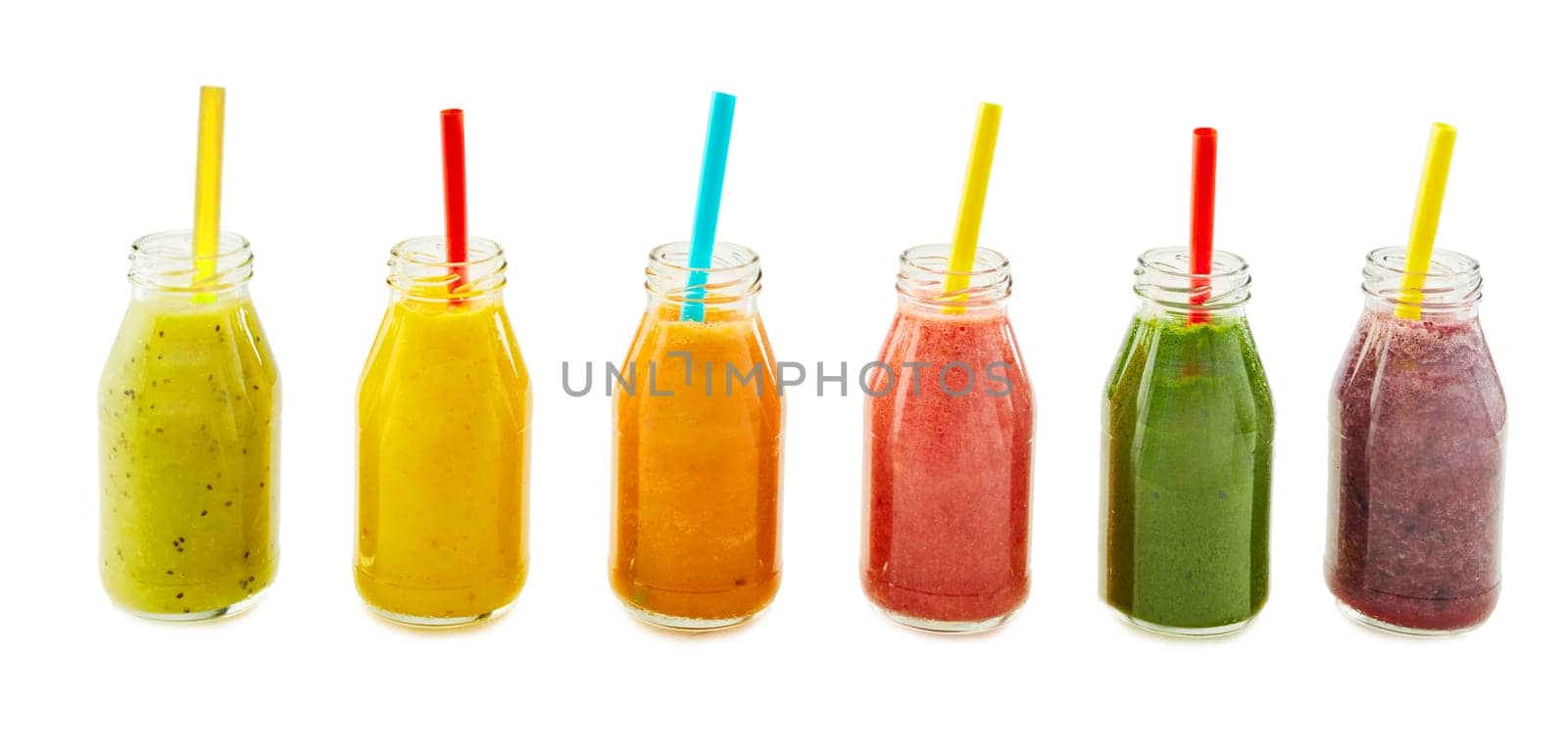 Row of assorted colorful fresh fruit and vegetable smoothies in glass bottles with straws isolated on white in panorama banner format for advertising