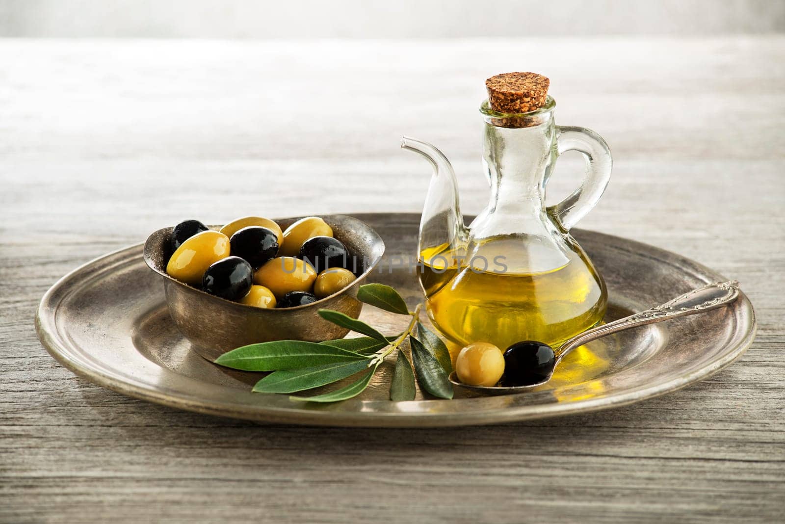 Olive oil and olive branch on wooden table