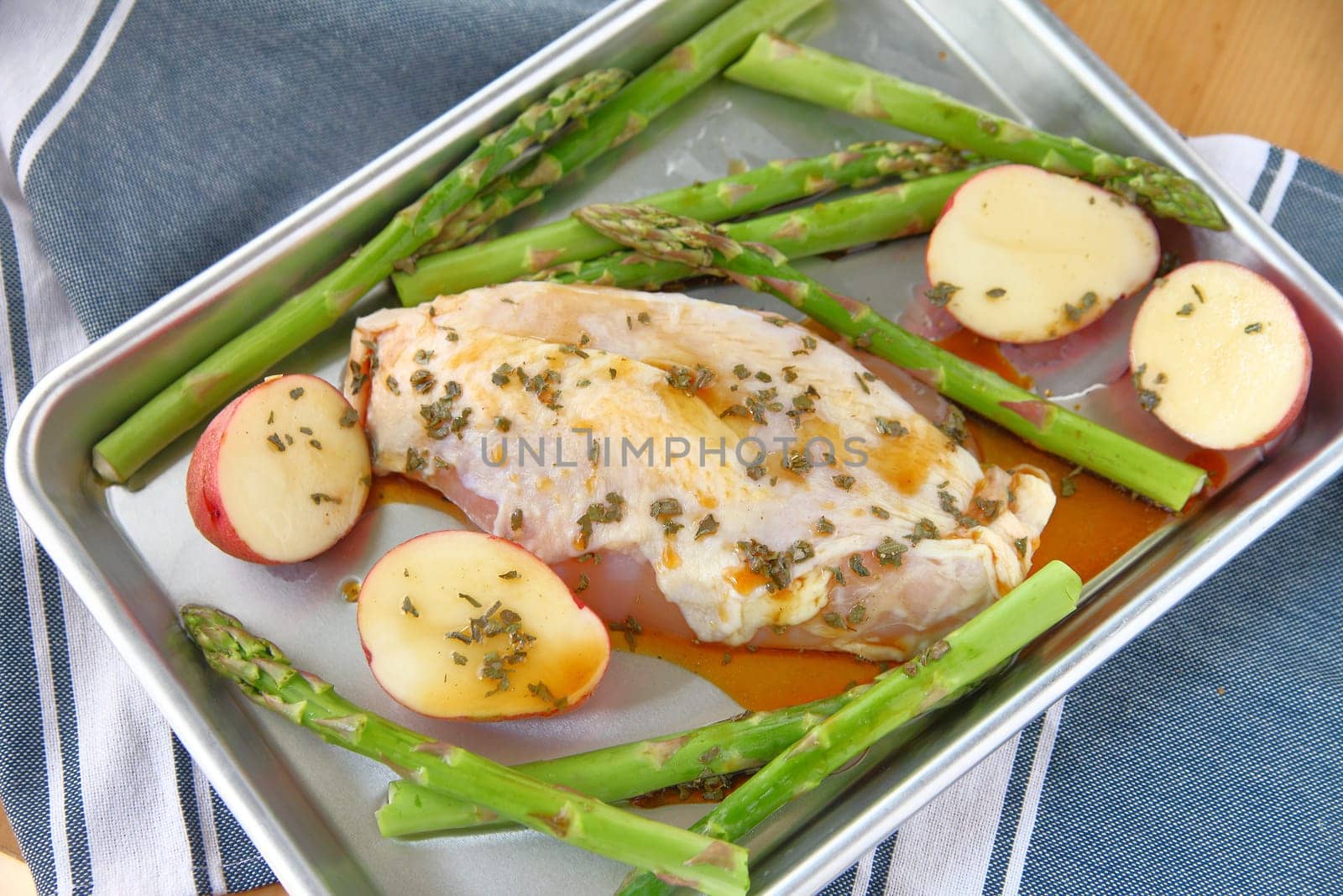 Chicken breast on half sheet pan with asparagus and small red potatoes.