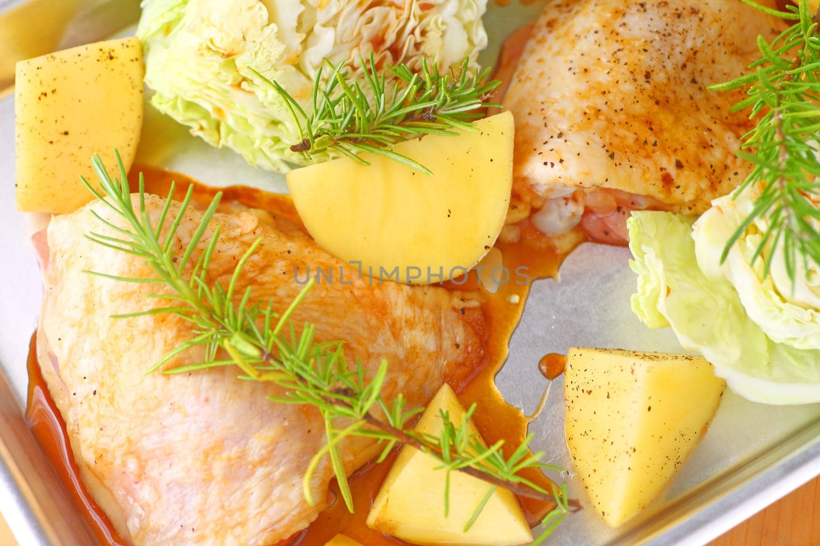 Small sheet pan dinner with marinated chicken thighs, Yukon gold potatoes, savoy cabbage and rosemary