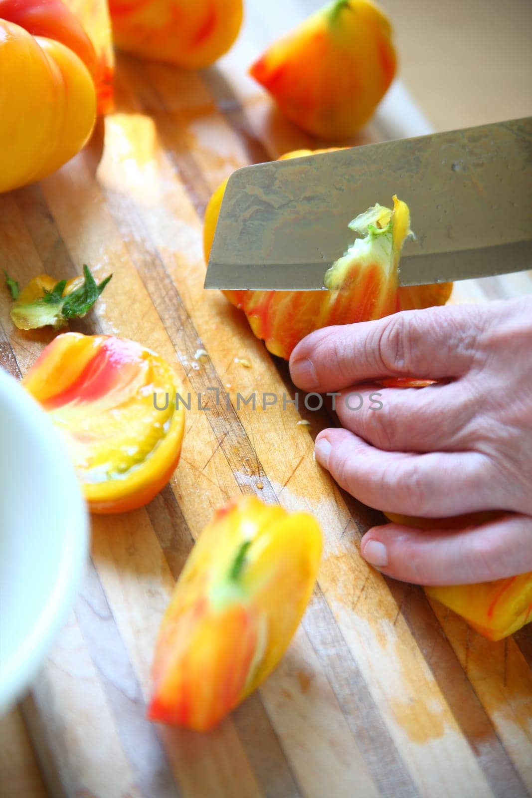 A man cuts up a colorful tomato, vertical view