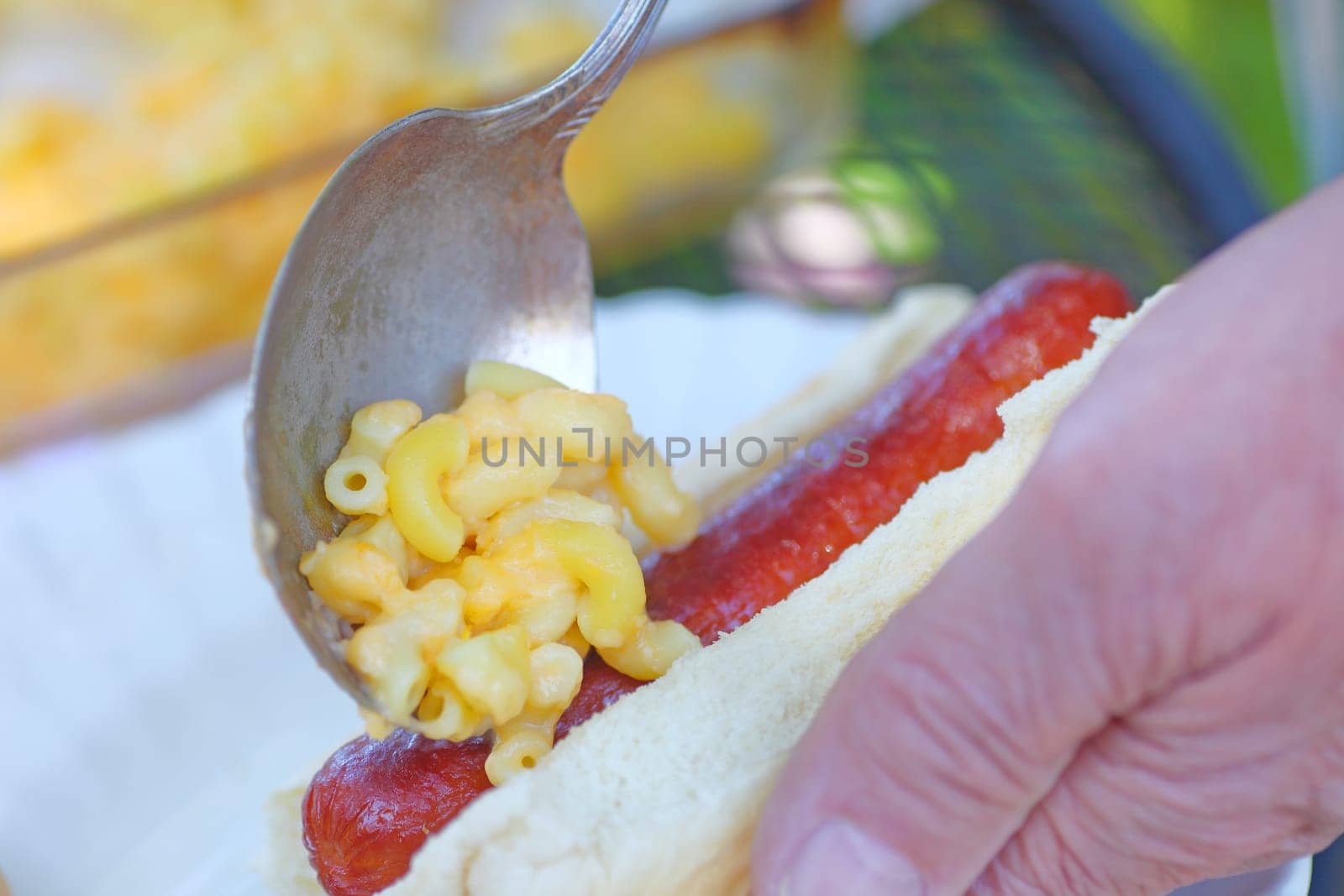 A man makes a mac ’n cheese dog outdoors