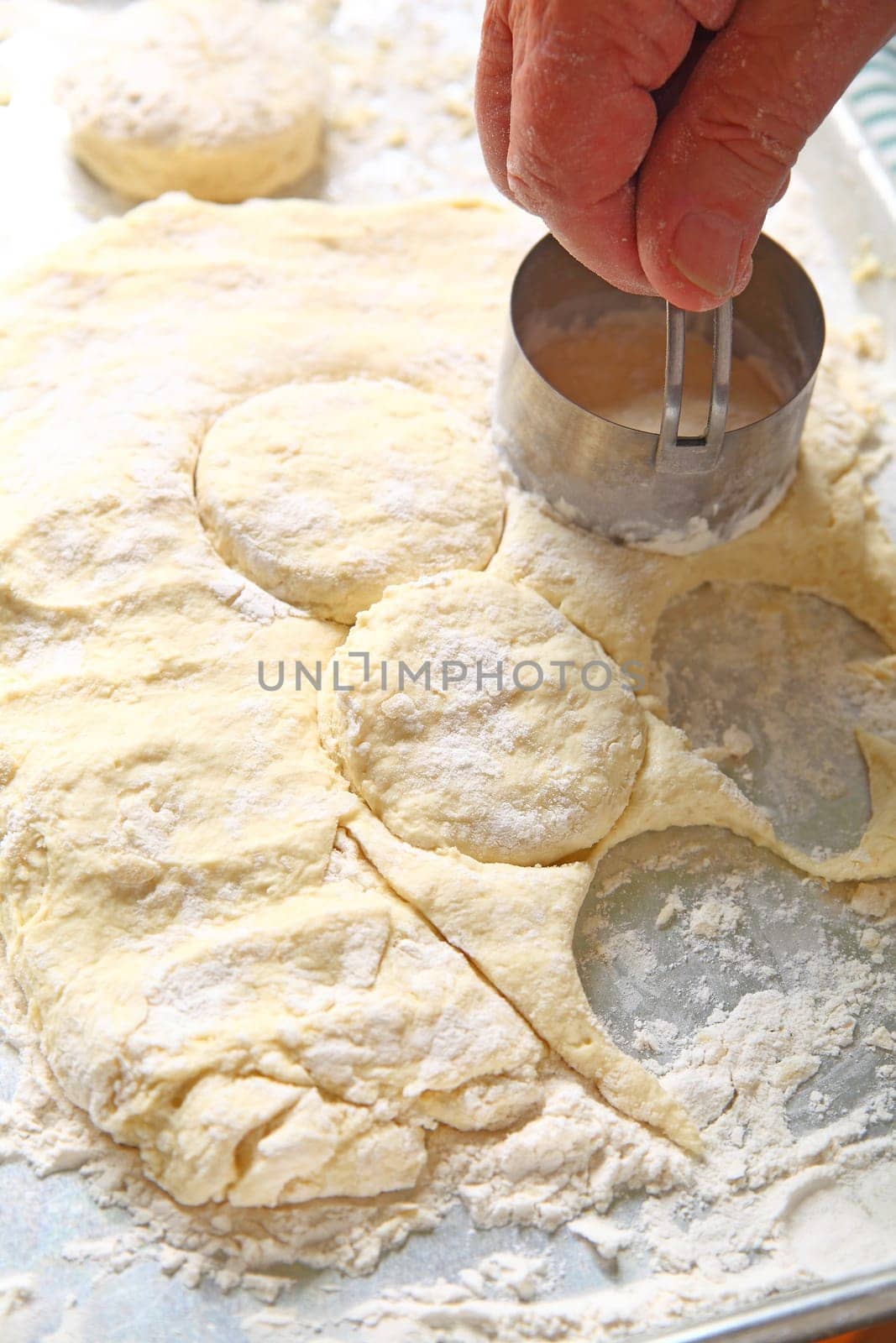 A man uses a metal cutter to make individual biscuits