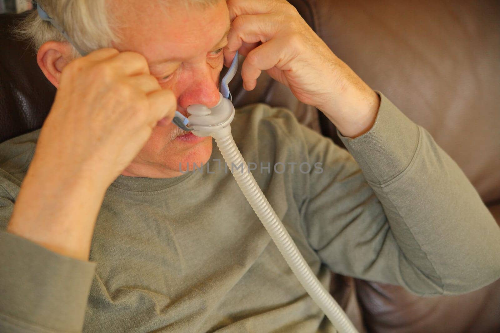 Older man puts on an apparatus for sleep apnea.