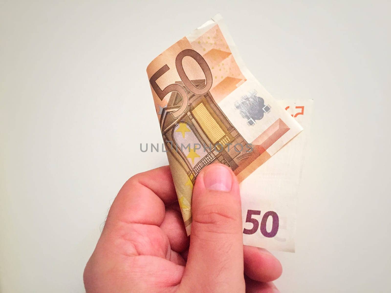 Male hand holding a folded 50 euro banknote