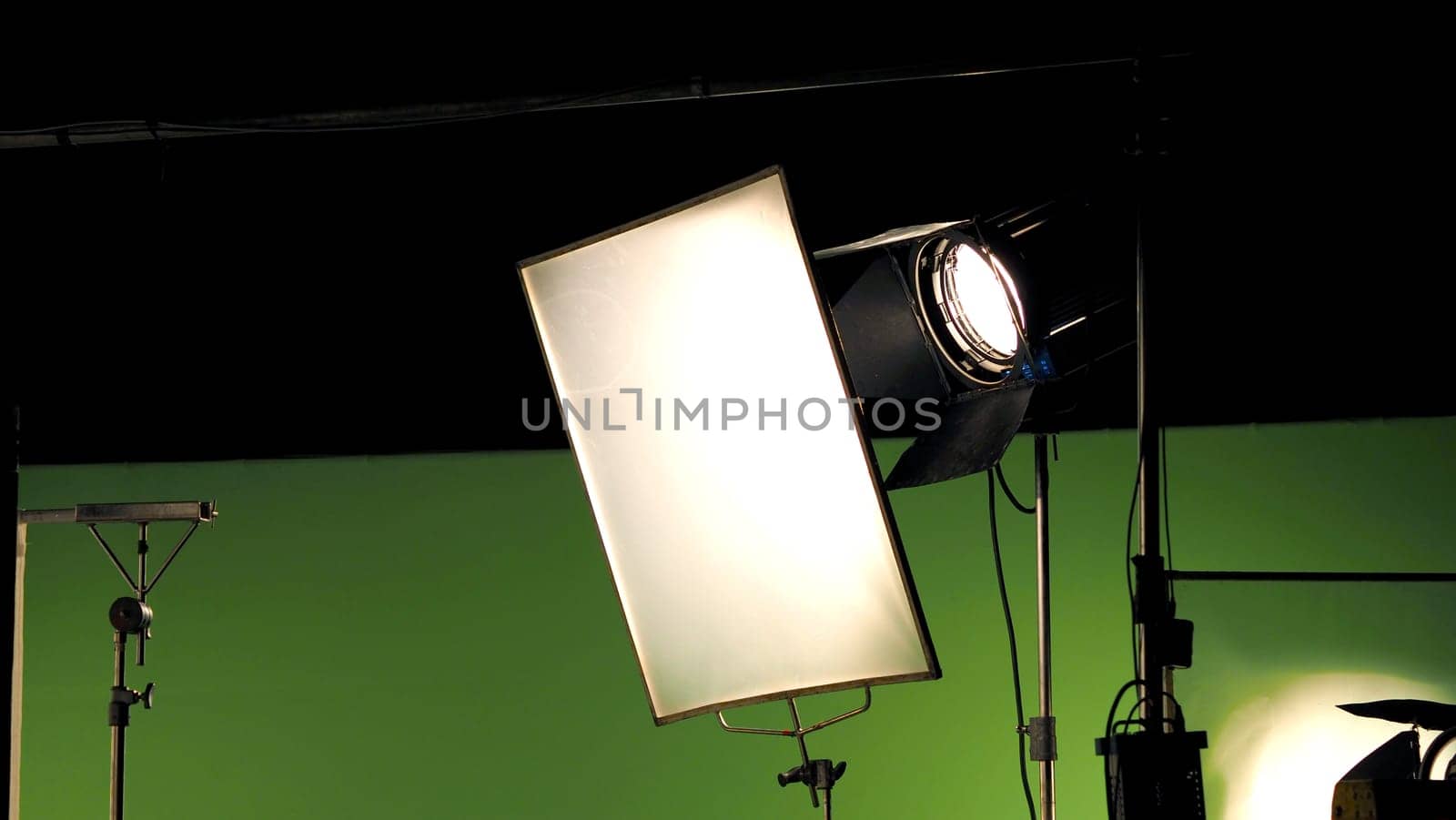 Big studio lighting kit 5000 watt with soft box on tripod and professional green screen background chroma key post production technique shooting or filming for movie or video commercial set up.
