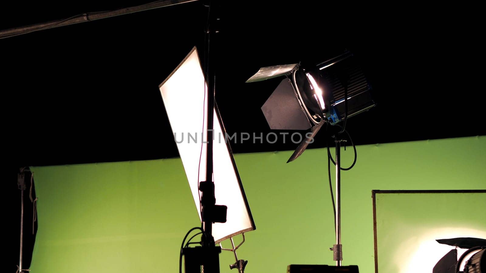 Big studio lighting kit 5000 watt with soft box on tripod and professional green screen background chroma key post production technique shooting or filming for movie or video commercial set up.