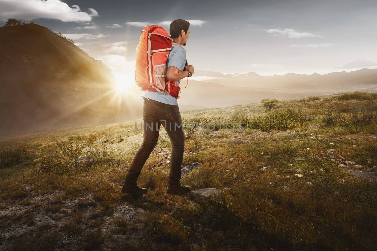 Attractive asian backpacker hiking the mountain with sunlight background