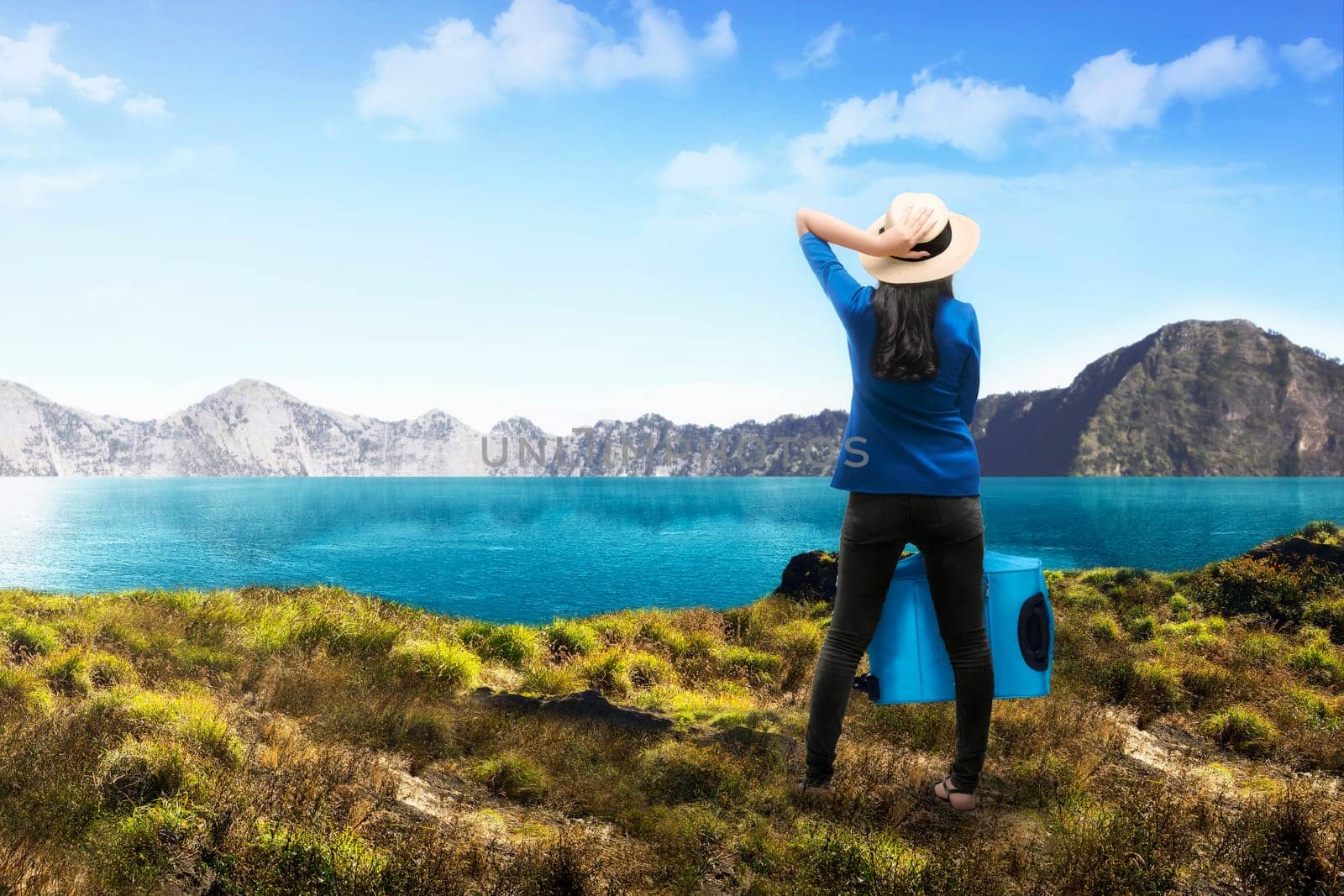 Rear view of asian female tourist with suitcase on the mountain