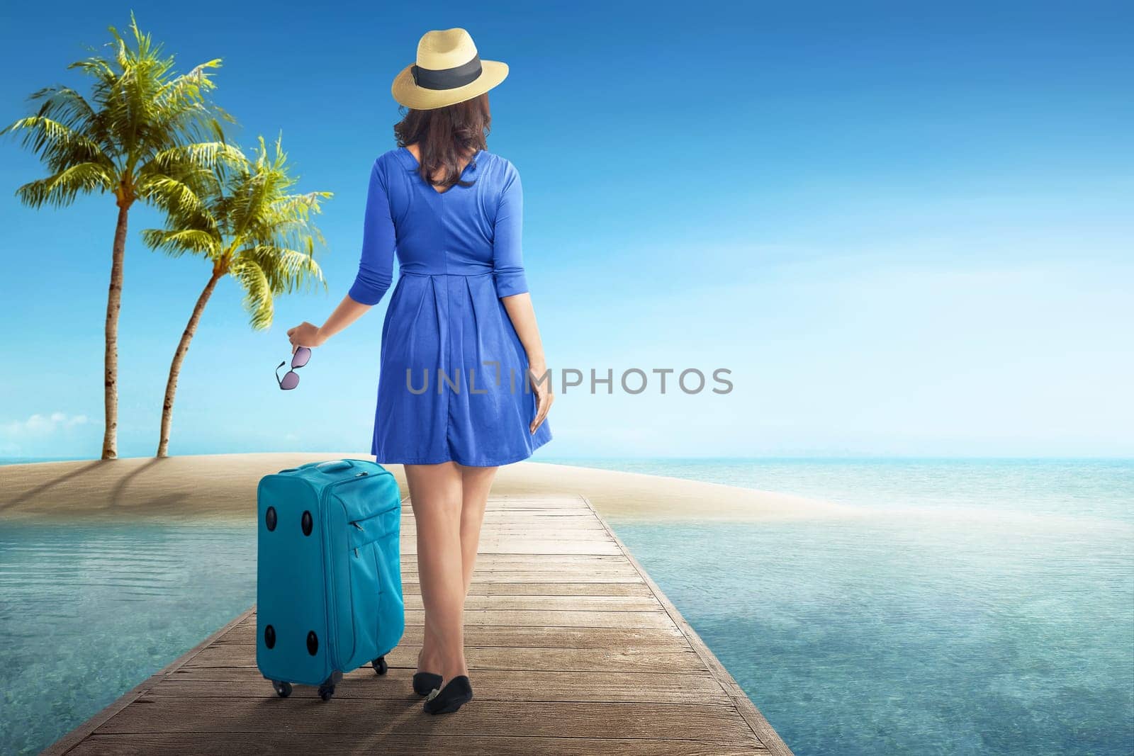 Rear view of asian woman with hat and sunglasses walking on wooden pier