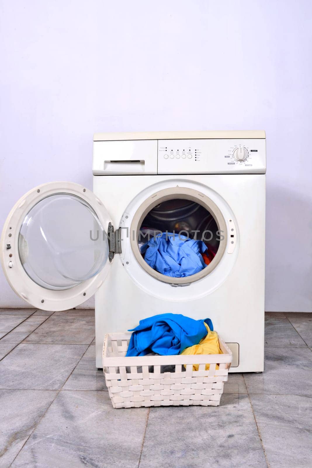 Clothes in basket and washing machine. Home appliance