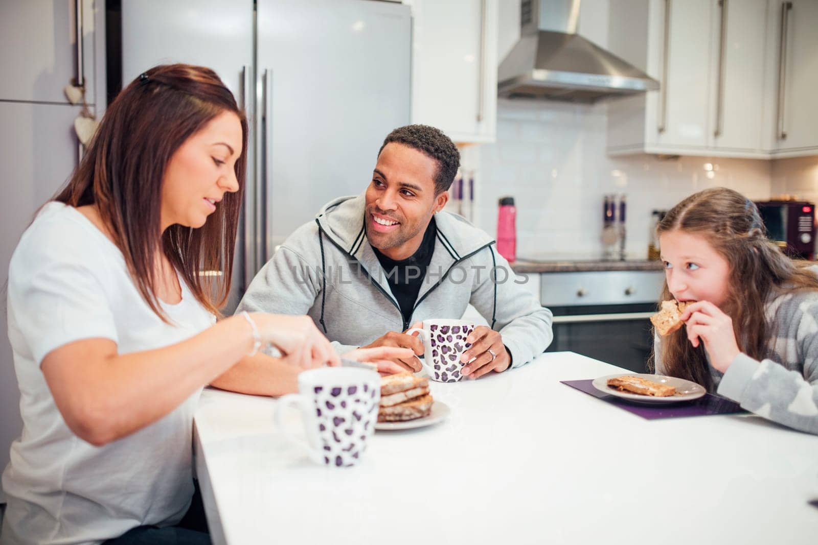 Little girl and her parents are enjoying toast for breakfast at home.
