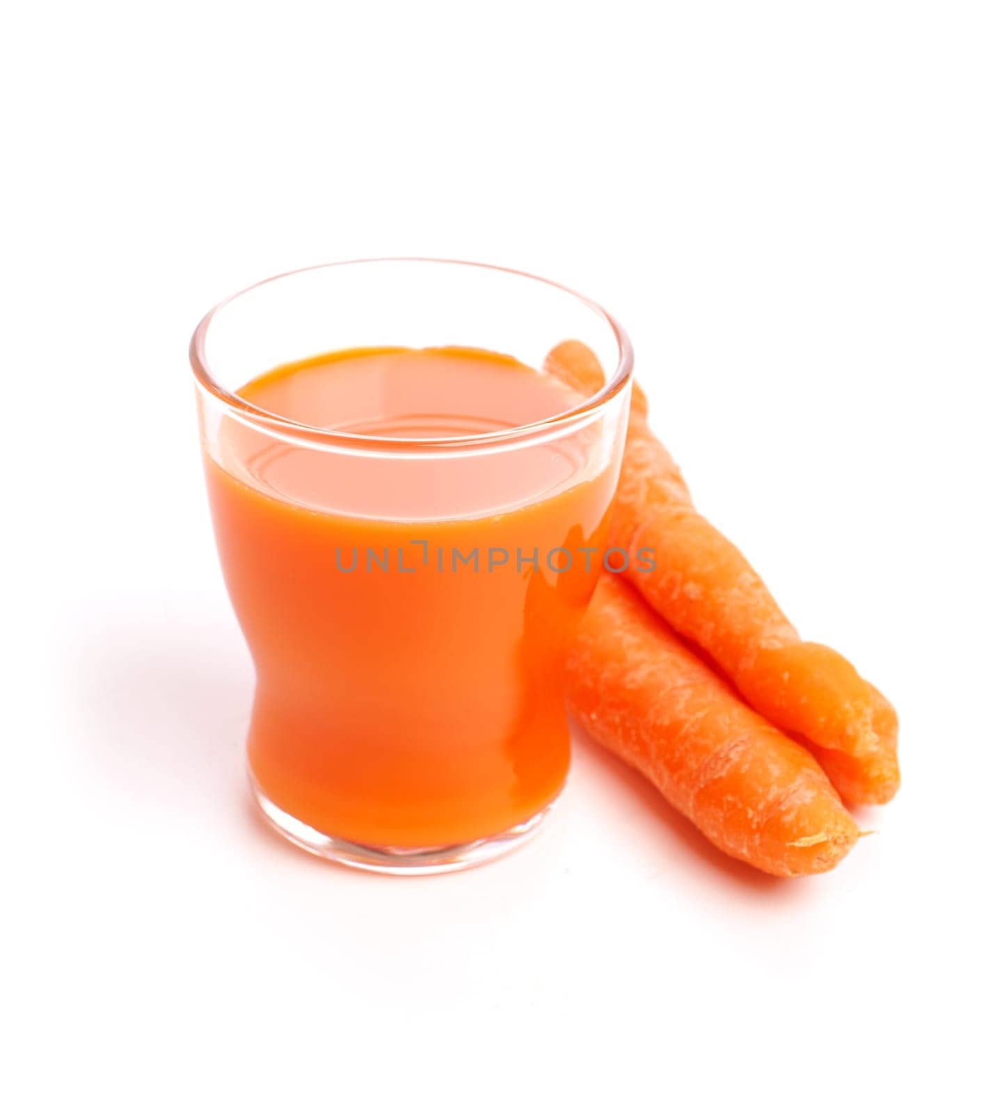 Juice of carrots on a white background, selective focus on the top of the glass