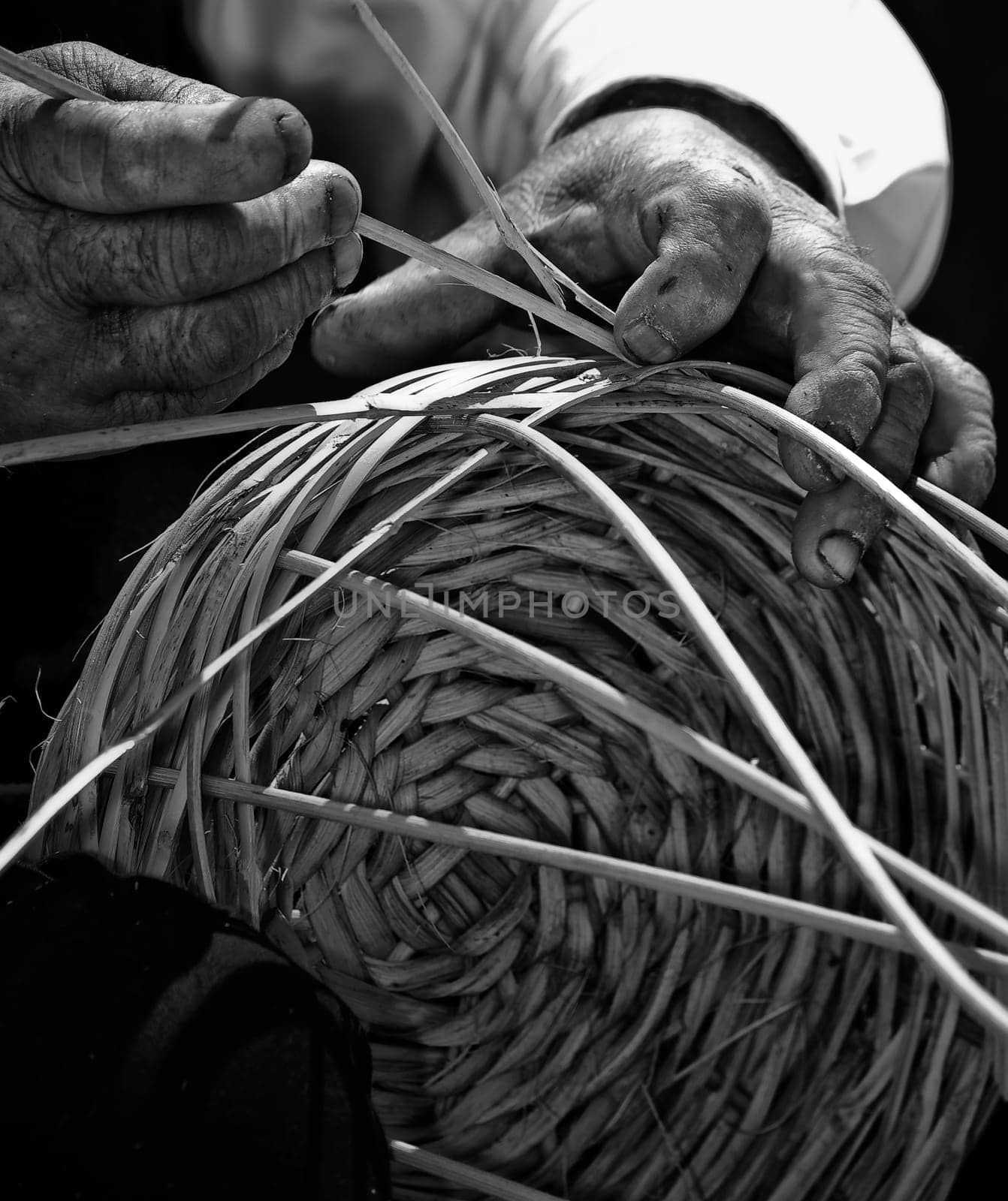 Detail of a man's hands in monochrome making a wicker basket