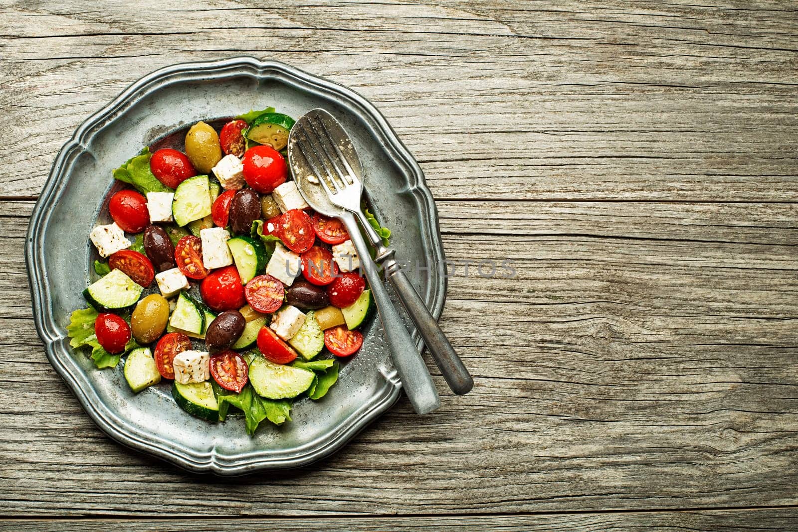 Salad with feta cheese and fresh vegetables on wooden background. Greek salad.