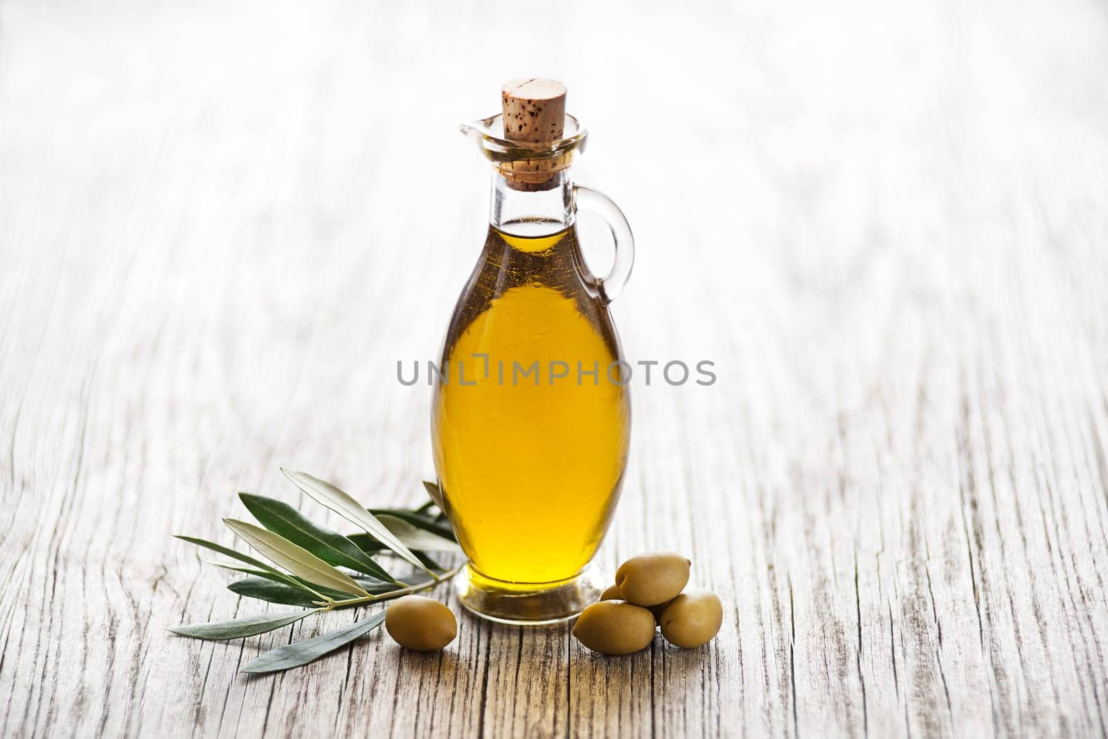 Olive oil with olive branch on wooden table
