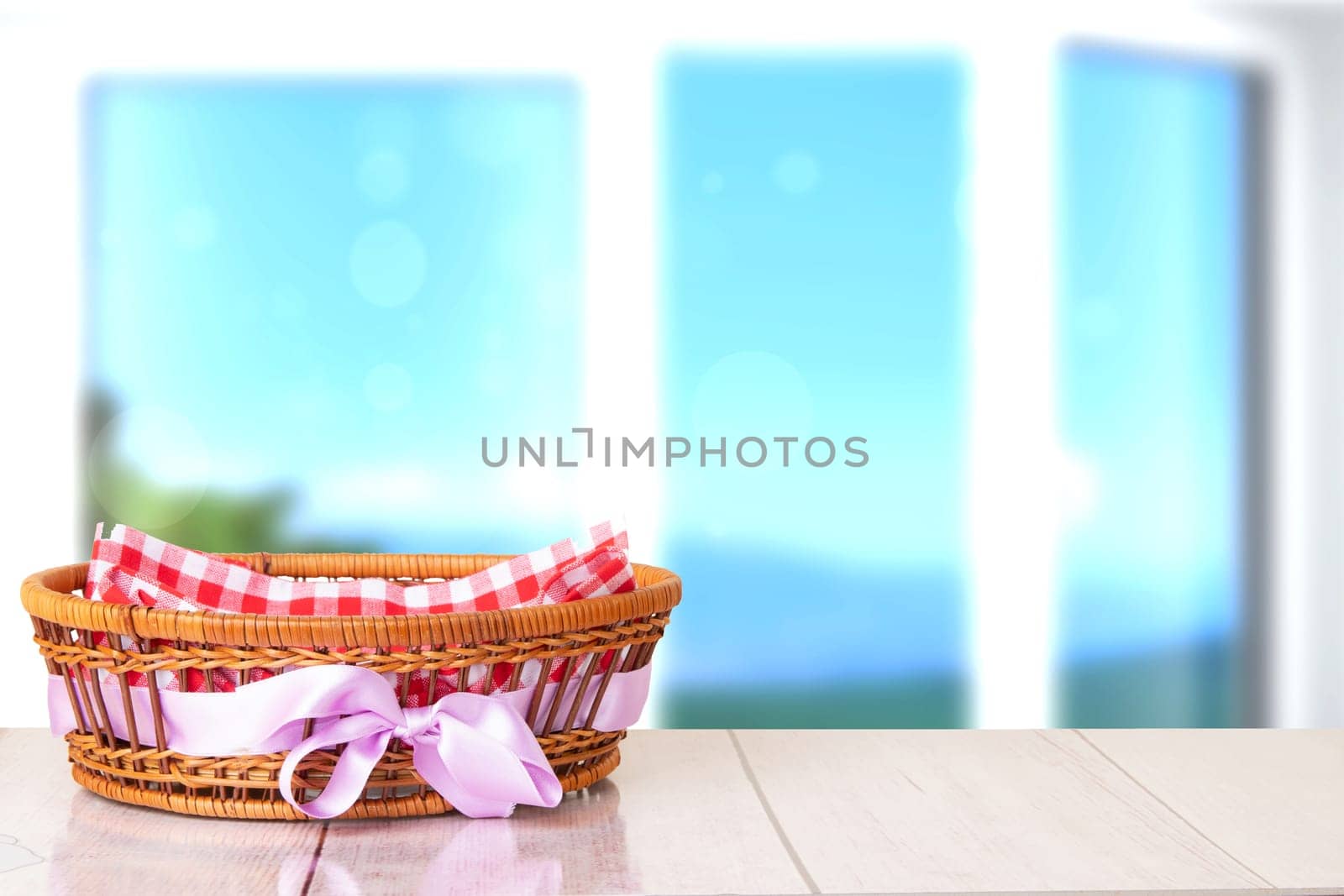 Empty basket with purple ribbon on wooden table with bright blurred natural background. For your food and product display montage.