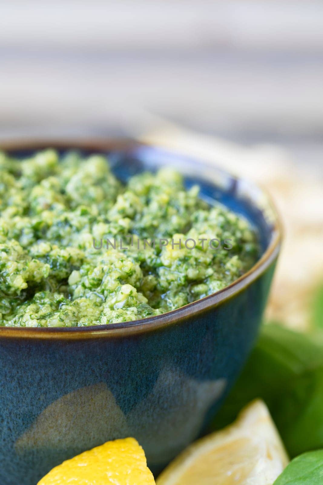 Close up of bowl of fresh pesto with lemons and some copy space at top