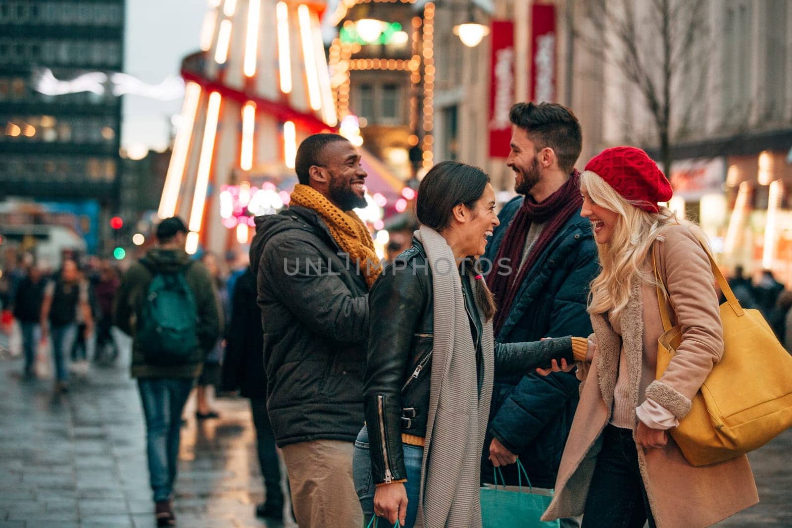 Side view of two couples meeting on a city street. Its winter and there is a fair ground ride on the street.
