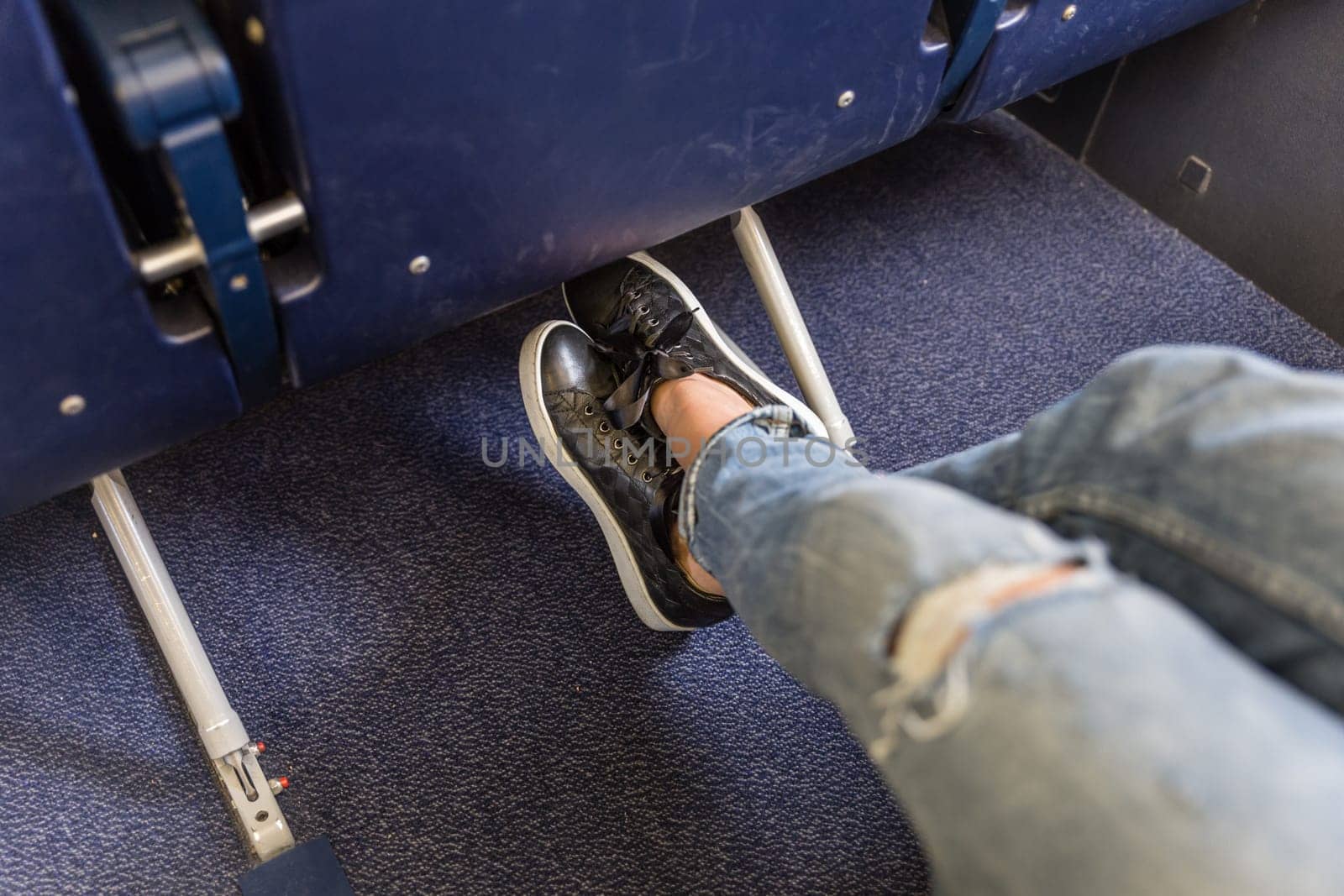 Female passenger stretching her legs on long commercial airplane flight. Exit seats with more leg space for more comfortable flight.
