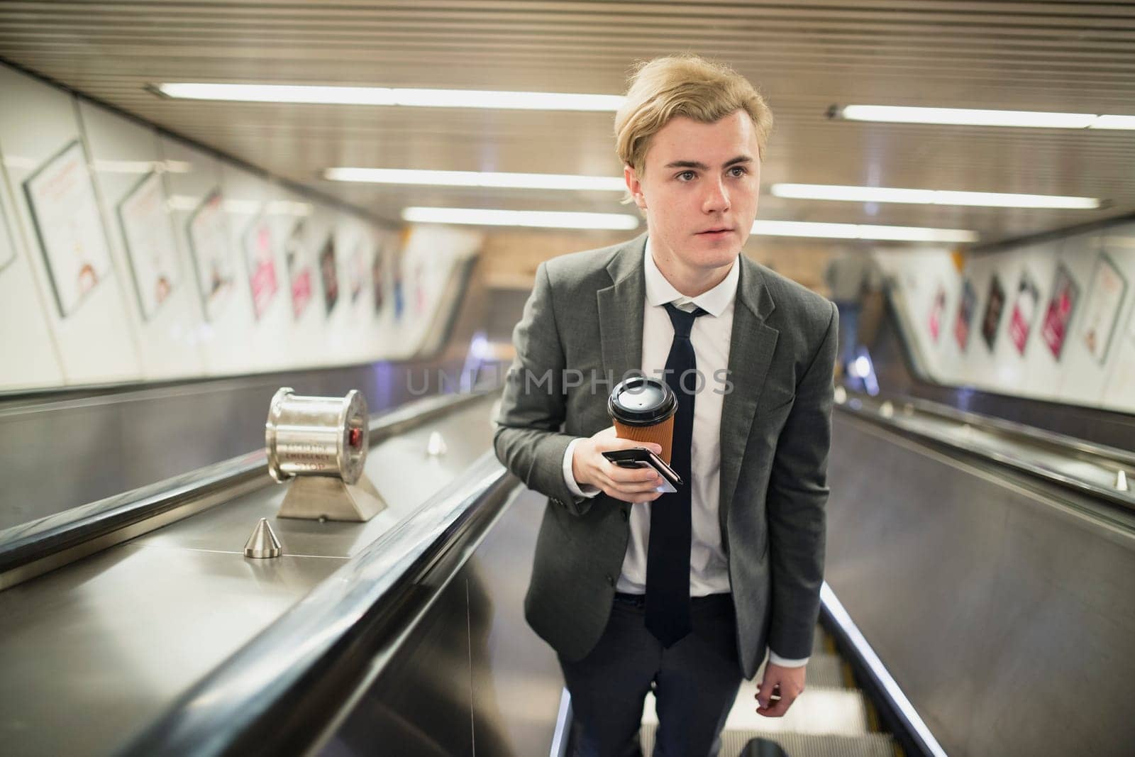 Young businessman moving up an escalator on his morning commute to work.