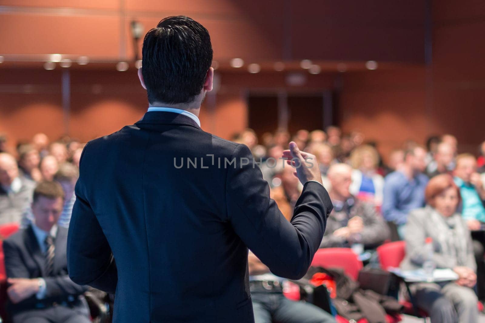 Speaker giving a talk on corporate business conference. Unrecognizable people in audience at conference hall. Business and Entrepreneurship event.