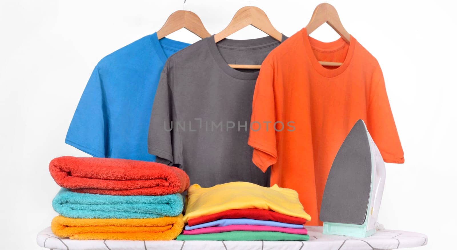 Electric iron and tidy clothes on the iron board isolated over white background
