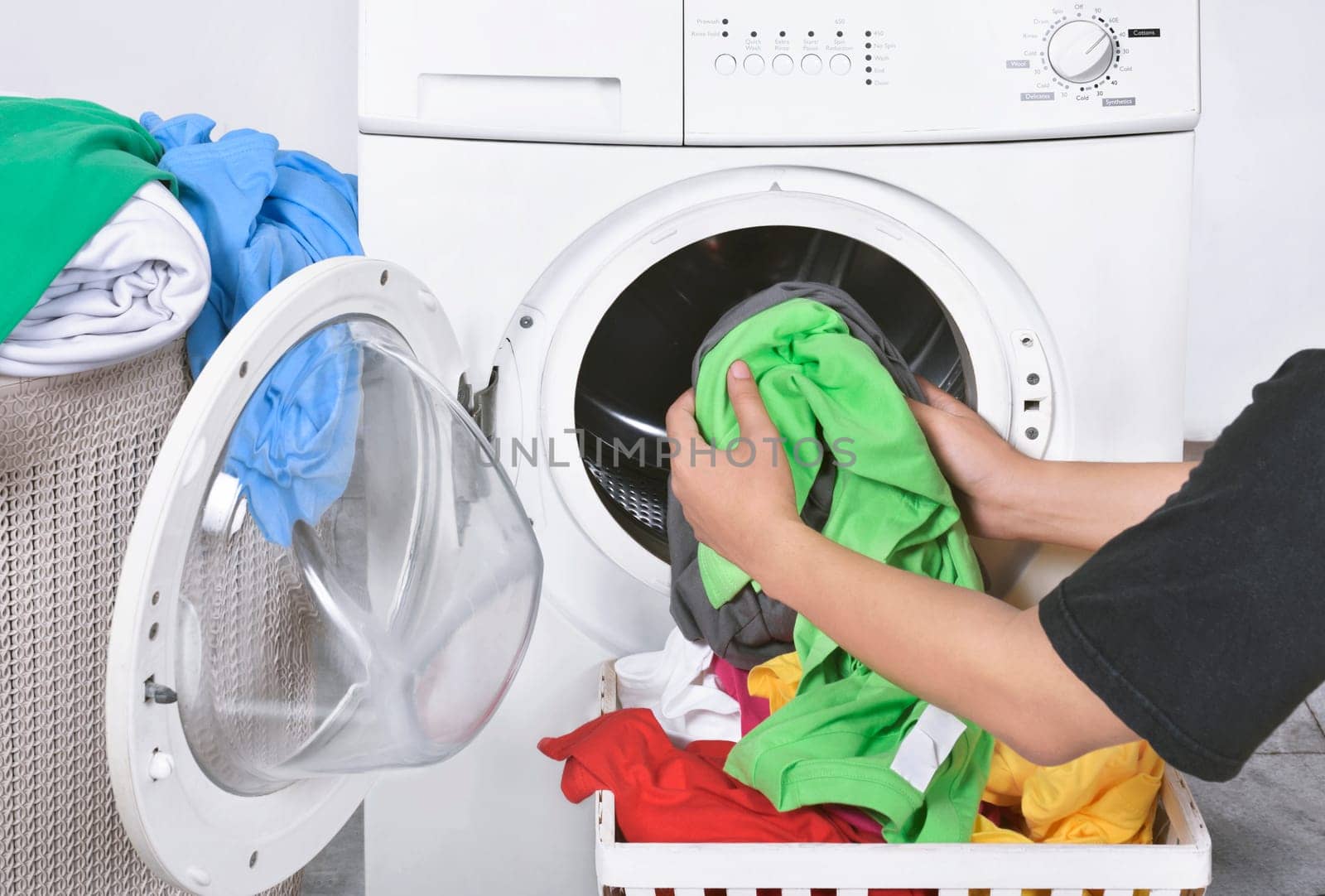 Male loading dirty clothes from basket to washing machine for washed. Home appliance