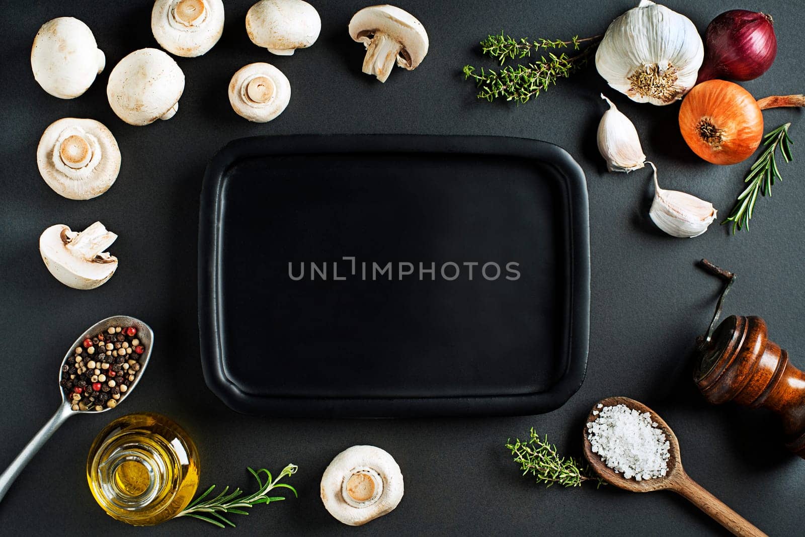 Mushrooms champignons with fresh ingredients on black background