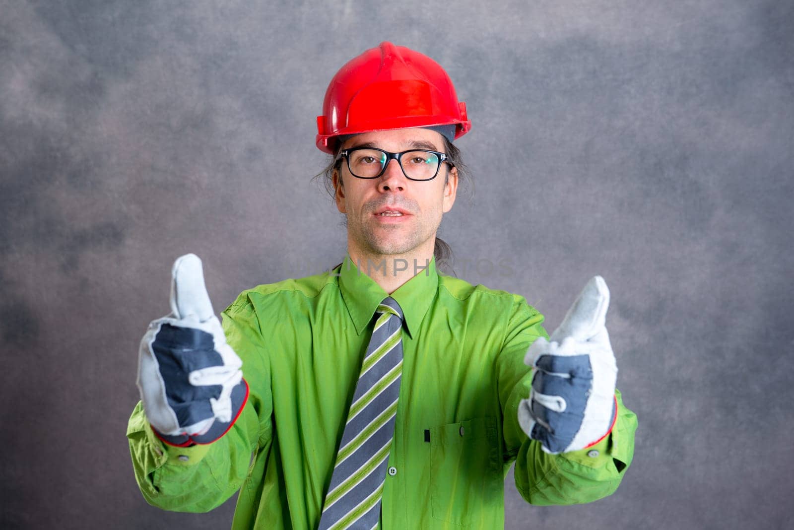 young architect in green shirt with red helmet and thumb up
