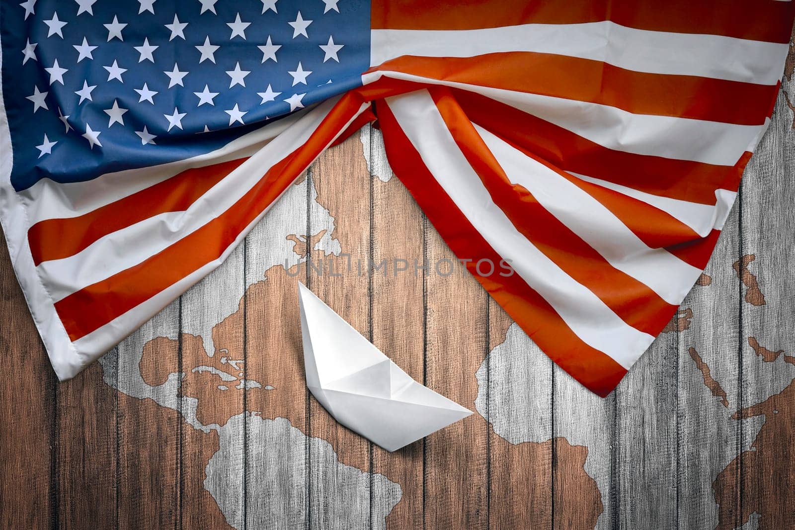 American flags and paper boat with wooden background. Columbus day concept