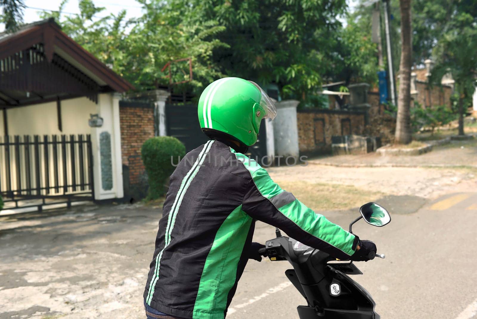 Portrait of motorcycle taxi driver pushing his motorcycle on the road side