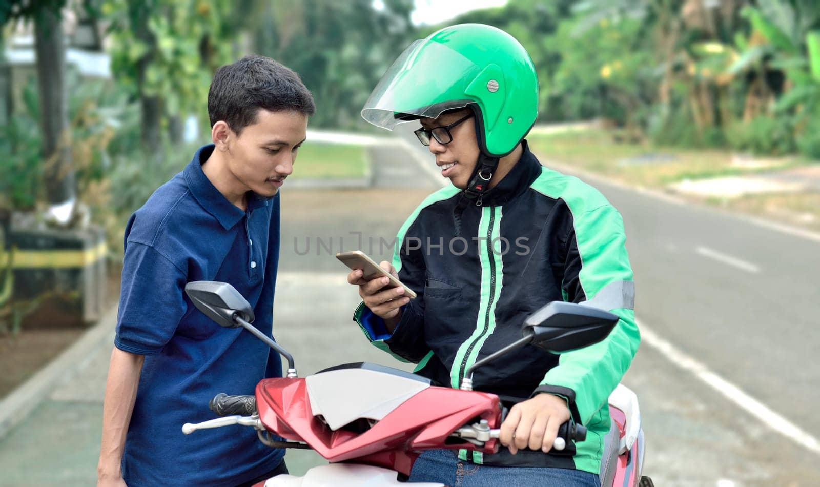 Young man motorcycle taxi driver checking passenger order before ride