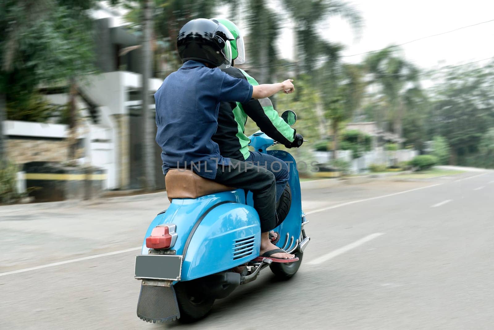 Rear view of passenger show direction to motorcycle taxi driver on the road