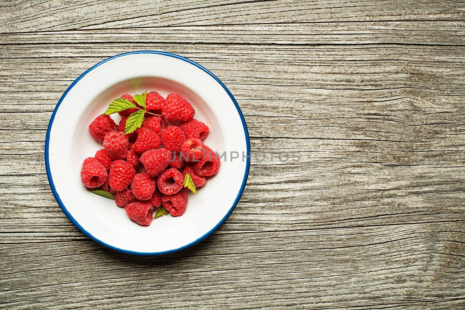 Raspberry berries with green leaf on wooden table. Healthy food with fresh fruit.