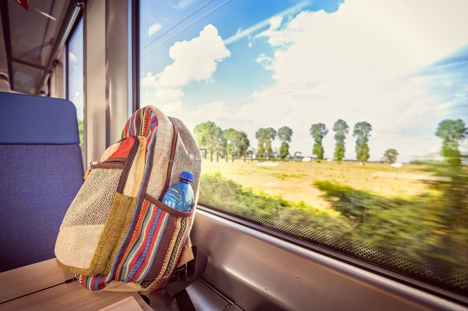 Colorful backpack on the train near the window. Conceptual image about traveling on vacation.