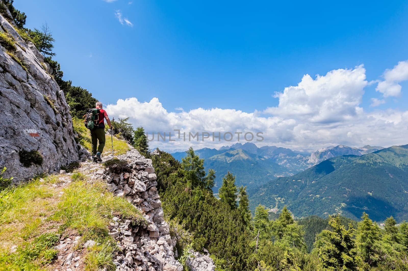 Hiker walks on a mountain trail with wonderful view to admire. Concept of adventure. Healthy lifestyle.